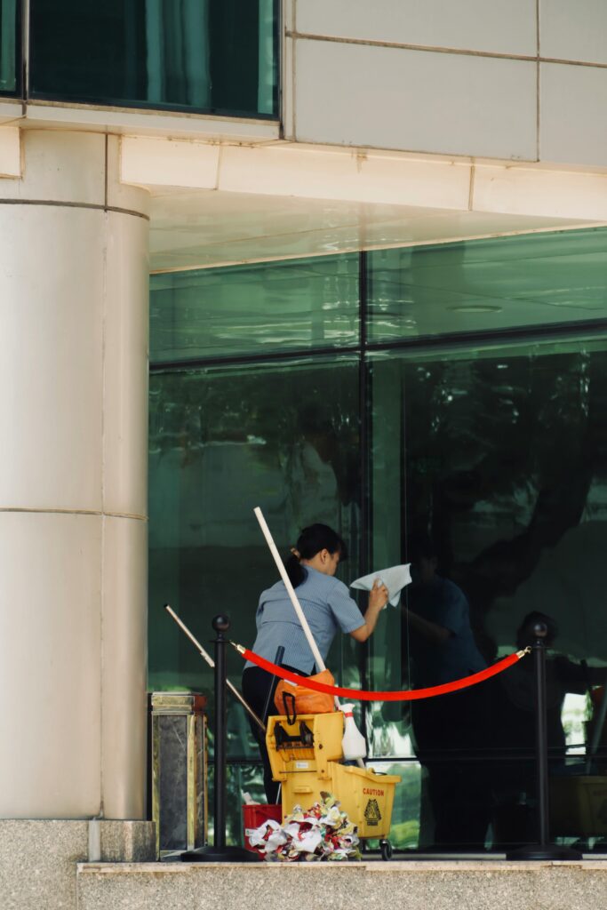 pexels-photo-20381389-20381389 Person cleaning a glass window of a tall building with cleaning equipment visible.